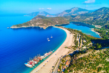 Aerial view of mediterranean sea bay with mountain, sandy beach and boats at sunny day in summer. Drone photo of Blue lagoon in Oludeniz, Turkey