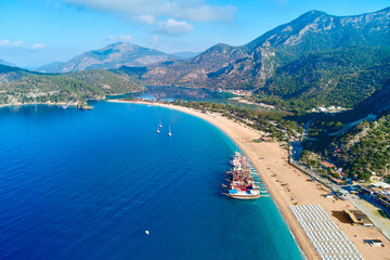 Aerial view of mediterranean sea bay with mountain, sandy beach and boats at sunny day in summer. Drone photo of Blue lagoon in Oludeniz, Turkey