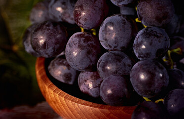 Close up photo of black grapes in a wooden bowl