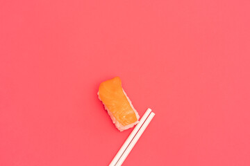 Traditional Japanese nigiri sushi with salmon with white chopsticks, separated on pink background