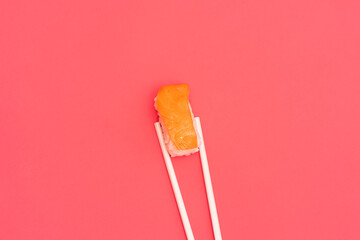 Traditional Japanese nigiri sushi with salmon with white chopsticks, separated on pink background
