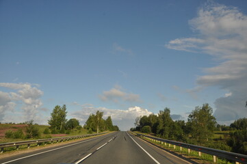 asphalt road, car trip view from the window around the field green grass beautiful sky