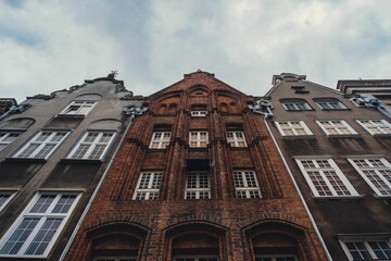 Low-angle view of old town building's facades under the cloudy sky in Gdansk