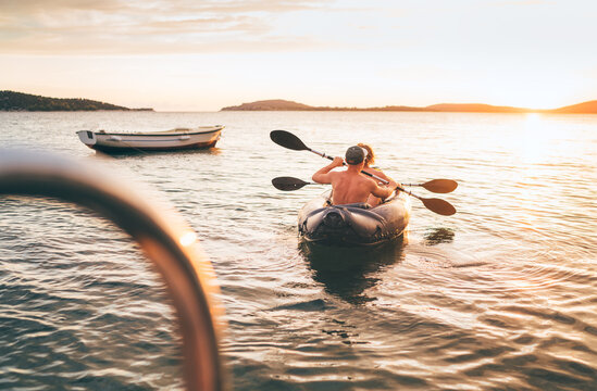 Two rowers on inflatable kayak rowing by the evening sunset rays Adriatic sea harbor in Croatia near Sibenik city. Vacation, sports, and a recreation concept image.