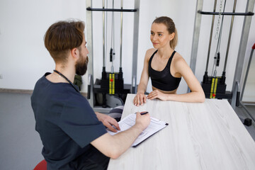 Young fitness woman listens to the recommendations of a physiotherapist doctor during treatment in a rehabilitation clinic after an injury