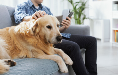 Man chatting with his phone and caressing his dog