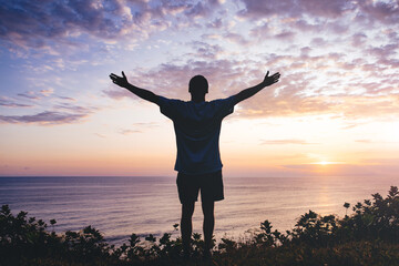Man with arms outstretched celebrating in beautiful inspiring sunset