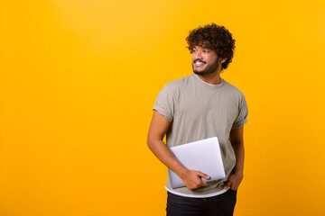 Waist up portrait of the smiling male person holding laptop in hands and smiling, Indian freelancer...