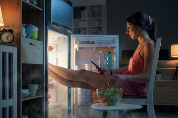 Fototapeta na wymiar Woman cooling herself in front of the open fridge