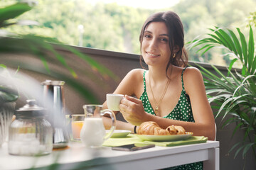 Happy woman having breakfast on the balcony