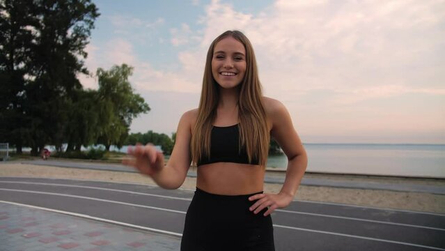 Fitness girl standing and showing the ok sign.Girl on the beach after working out smiles for the camera