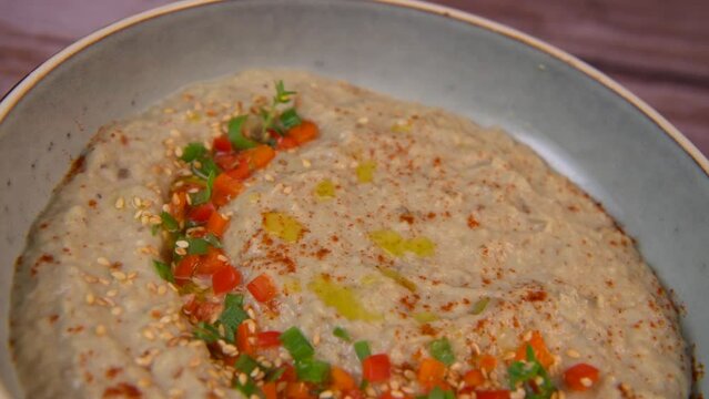 Traditional arabian eggplant dip baba ganoush with herbs and smoked paprika on a wooden background. High quality 4k footage