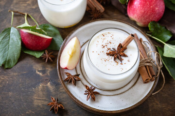 Autumn apple drink. Homemade banana apple smoothie with apples, yogurt, cinnamon, spices or lassi in a glass on a rustic table. Copy space.