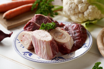 Marrow bones, meat and vegetables - ingredients for preparing beef bone broth or soup