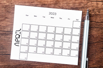 The April 2023 Monthly calendar for 2023 year with pen on wooden table.