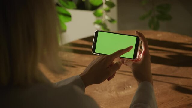 Handheld close up of a caucasian woman hand swipe on a smart phone with green screen croma key
