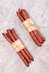 Polish kabanosy sausage. Thin dry sausage, wrapped with eco food paper and tied with string, on gray marble background.