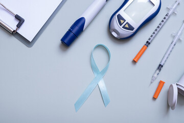 Fototapeta na wymiar Blue ribbon and glucometer, medical supplies on color background top view with copy space. World diabetes day concept