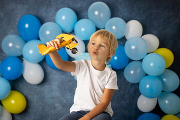 Fototapeta premium Cute preschool boy, playing with airplane, balloons and birthday decoration
