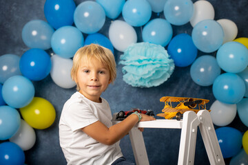 Cute preschool boy, playing with airplane, balloons and birthday decoration