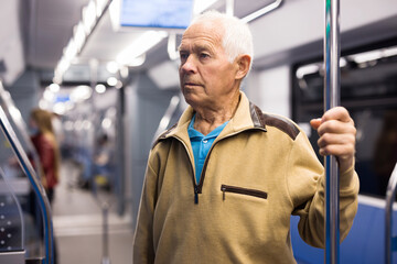 Old man standing in subway car