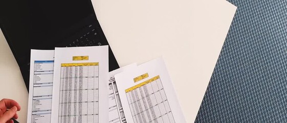 Slow motion footage of a person checking balance sheet and loan amortization table. Finance
