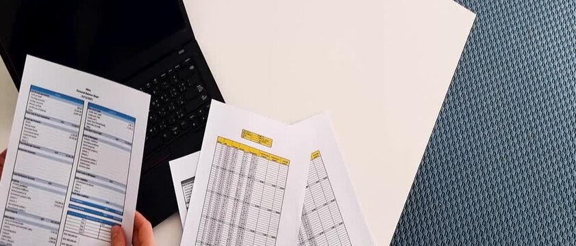 Footage of a person checking balance sheet and loan amortization table. Finance