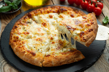 A slice of hot Italian pizza with stretching cheese. Pizza four cheeses with basil.