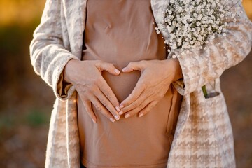 Midsection of pregnant woman standing at autumn park