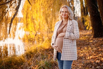 Caucasian mature pregnant woman standing in autumn park