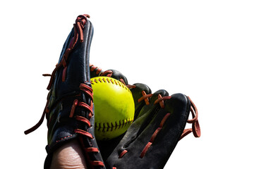 a green softball sits in a red and black leather glove outside on a sunny day 