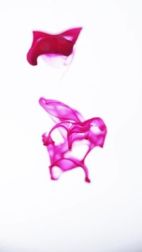 Vertical video. Purple magenta ink paint drops in water slow motion abstract background. Smoke cloud swirl, splash, mix and dissolve underwater	