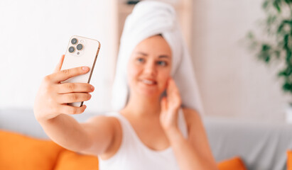 a young beautiful girl takes a selfie on her smartphone in the morning after a shower. selective focus