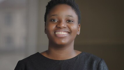Front view closeup portrait happy toothy smiling with white healthy teeth satisfied African American woman biracial 20s girl with short hair natural make-up lady smile posing indoors looking at camera - Powered by Adobe