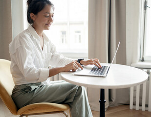 A woman in the office is working on a project online using a laptop computer.