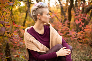 Stylish hipster woman smiling and playing with autumn leaves in park. Autumn woman, fall