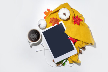 Cozy fall background with coffee cup, tablet notebook, ear-pods, white, orange pumpkins, autumn leaves decor on white home office table background. Autumn still life composition flatlay