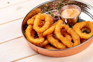 Onion rings fried in breading with cheese sauce