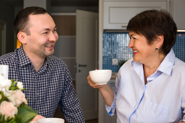 Sons congratulate mom on the holiday.Mother and son talking over cup of tea. Holiday celebration. 8 march,birthday