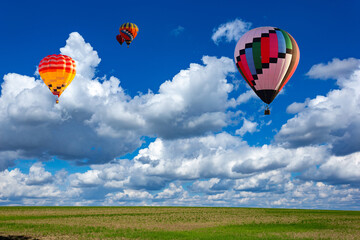 Colorful hot air balloons over green rice field.