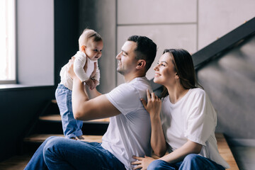 Young couple lying together on blankets on their living room floor at home with their adorable baby daughter