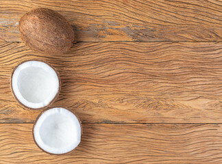Coconut and cracked half fruit over wooden table with copy space