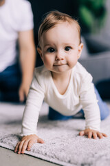 Fototapeta premium Childhood, babyhood and people concept. Happy little baby boy or girl sitting on floor at home