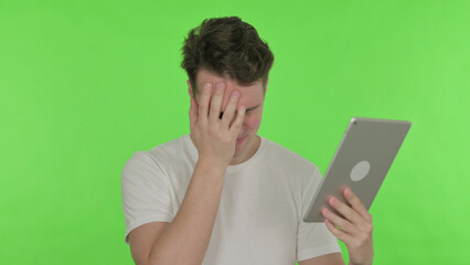 Young Man Reacting to Loss on Tablet on Green Background