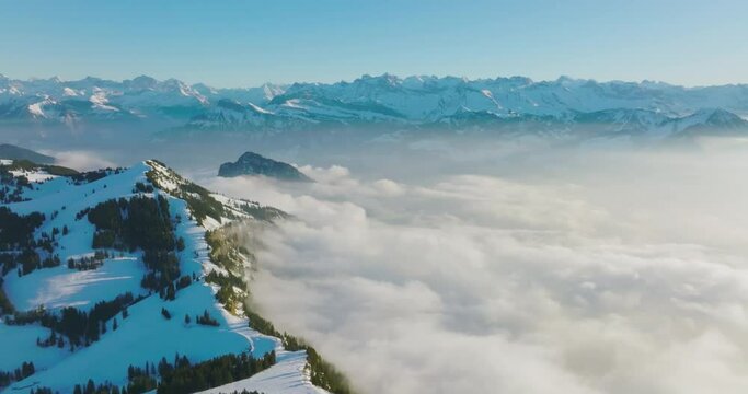 Aerial drone fly above the clouds over summit of Mount Rigi (Rigi Kulm) and Lake Lucerne underneath, Switzerland. Amazing snow and fog covered Swiss alps mountain peaks and winter scenery landscape.
