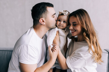 Parenthood and people concept - happy mother, father and baby daughter playing at home