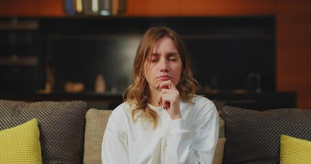 Pensive worried young caucasian woman watching soap opera, television series, sigh heavily, thinking, sitting on couch