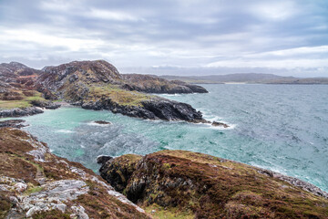 Fototapeta na wymiar Rugged Scottish west highland coast with breaking aqua waves and heather covered rocks