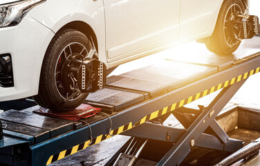 Car on stand with sensors on wheels for wheels alignment camber, Car mechanic installing sensor...