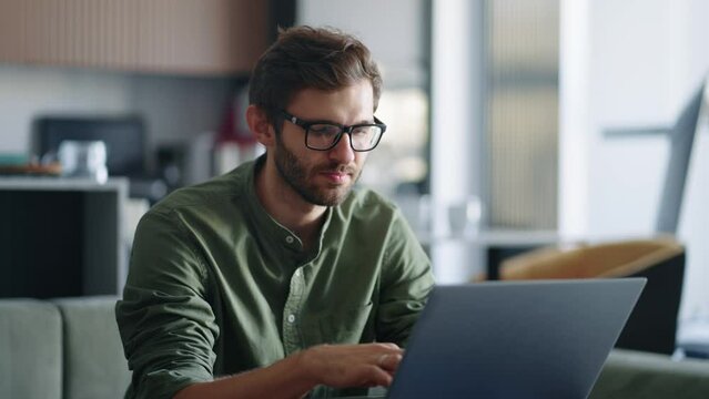 portrait of handsome man with glasses surfing internet by laptop at home, search query in browser